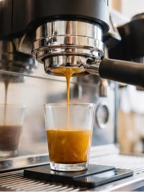 Frischer Espresso läuft aus dem Siebträger in ein Glas